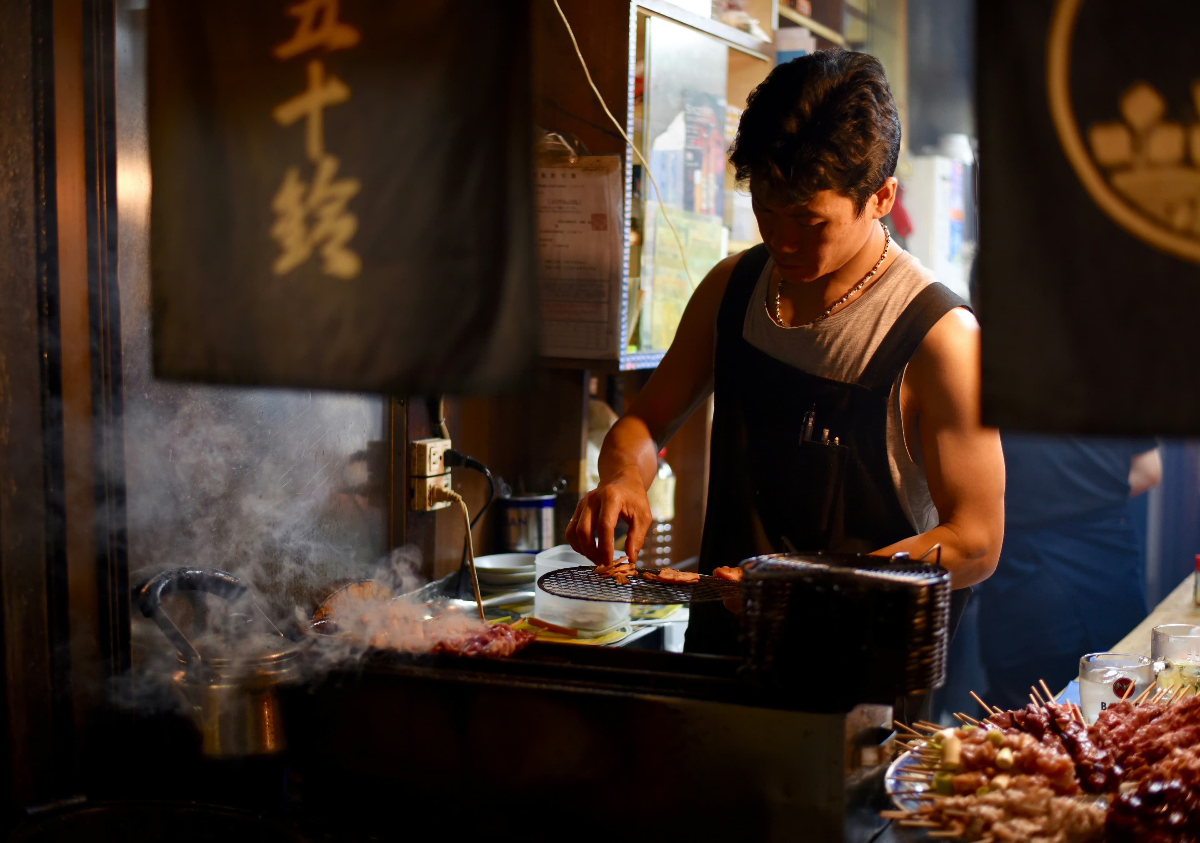 Yakitori counter with glowing charcoal embers beneath skewers
